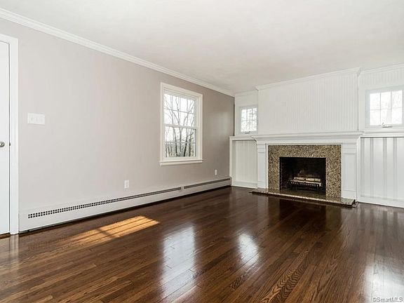 Updated living room with new windows, new stone trim around the fireplace, built-in shelves and beautifully refinished hardwood floors.