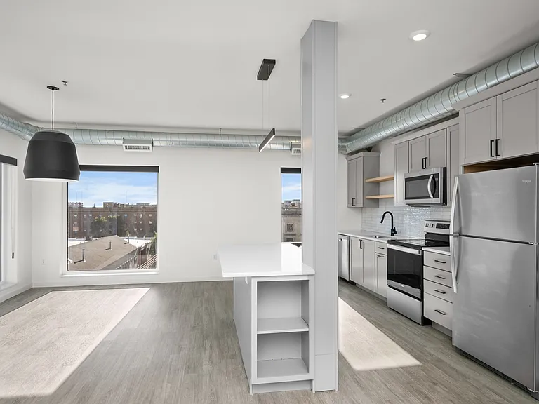 Modern open-plan kitchen with sleek stainless steel appliances, ample natural light, and stylish industrial ceiling details. Modern open-plan kitchen with sleek stainless steel appliances, ample natural light, and stylish industrial ceiling details.
