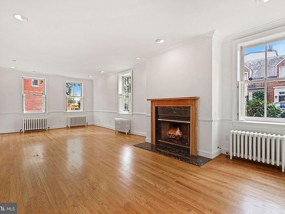 Living Room with gas fireplace, HWF, several windows and radiator heat.