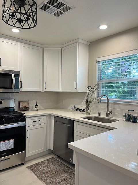 Beautiful kitchen with white shaker cabinetry, white quartz counter top, white subway tile backsplash, tile flooring, stainless steel appliances including gas stove, refrigerator with water/ice dispenser, dishwasher, microwave.