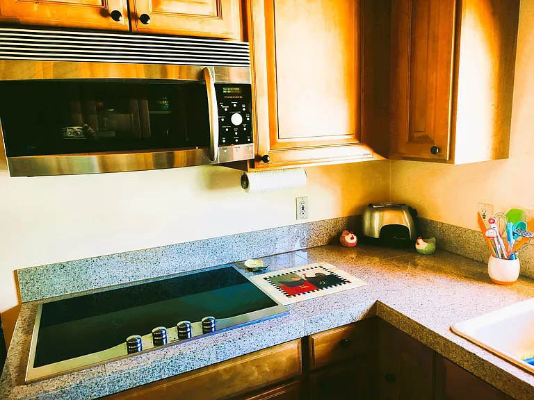 Modern Kitchen with Window over Sink & High Quality Appliances: Convection Microwave, Glass Stovetop, Oversized Refrigerator, Toaster Oven, Electric Tea Kettle, Glass Cabinet Doors, Breakfast Bar & Stools & a vast assortment of Kitchenware, etc.