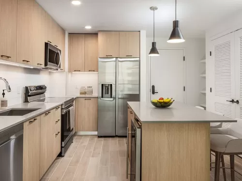 Kitchen with stainless steel appliances, grey quartz countertops, white tile backsplash, and hard surface flooring - Avalon Merrick Park