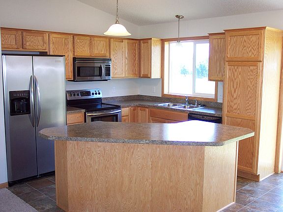 Kitchen features valuted ceiling, center island with bar ove