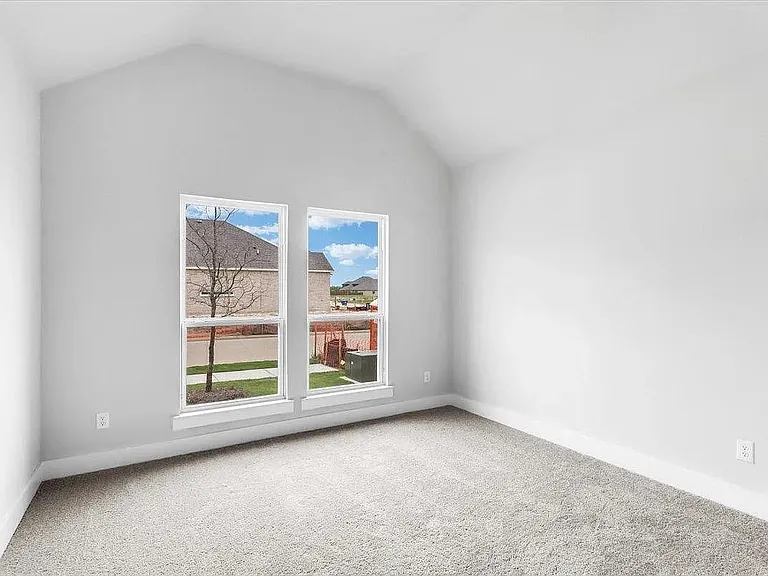 Vaulted ceiling room featuring two large windows with white trim, light gray wall paint, white baseboards, and neutral-toned carpeting