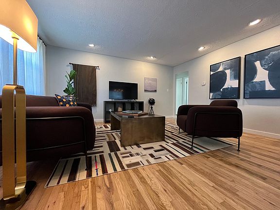 Upscale living room furnishings and restored hardwood flooring throughout