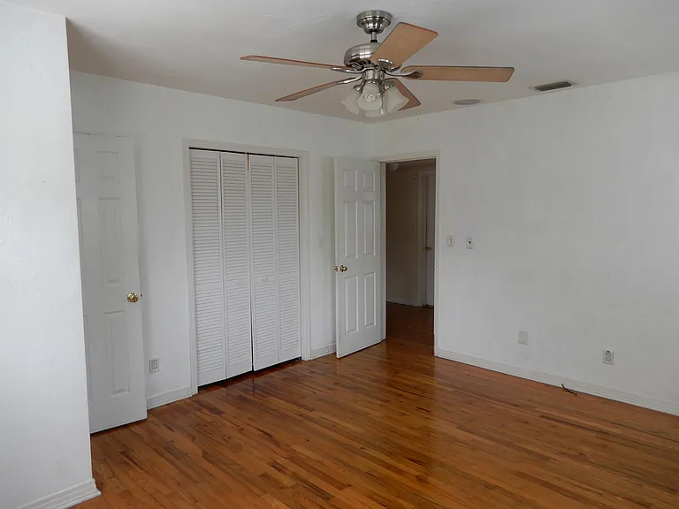 Interior view of master bedroom with custom built closet and ceiling fan with lights.