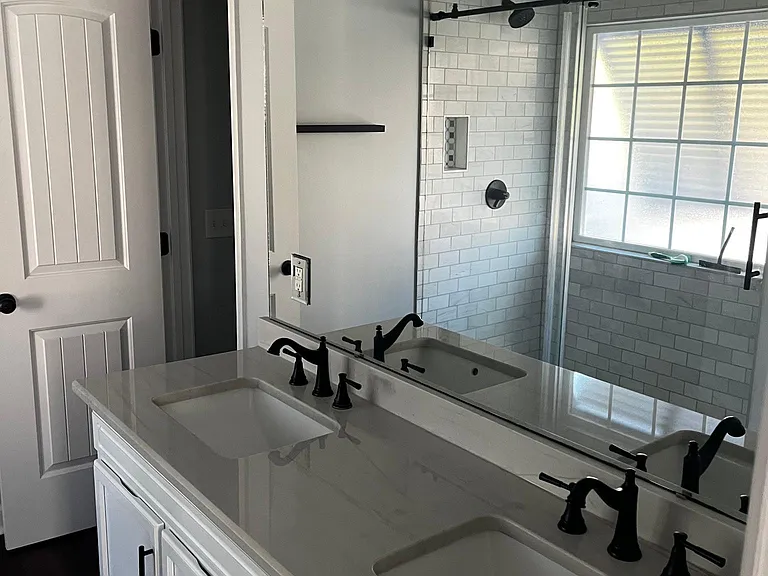Large dual-sink vanity with extensive cabinetry, full-width mirror, and views into the walk-in shower.