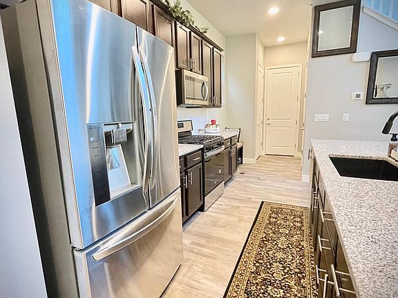 Kitchen with large LG refrigerator, gas stove, stainless steel microwave and dishwasher.