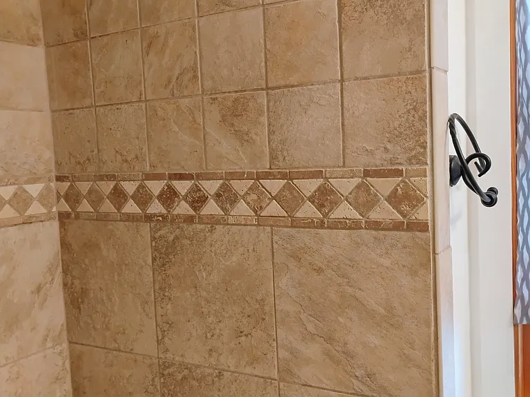 Tile Shower surround with shower head. Has a cast iron bathtub.