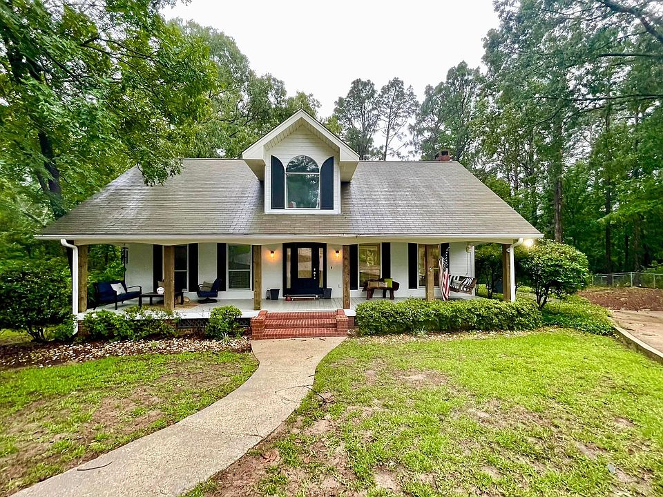 Huge front porch with raw timbered columns stretches across the house to offer a welcoming place to receive guests or just sit and relax on the swing.
