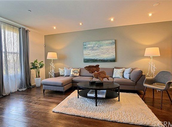 Living room with high ceiling, birch wood flooring and custom window draperies