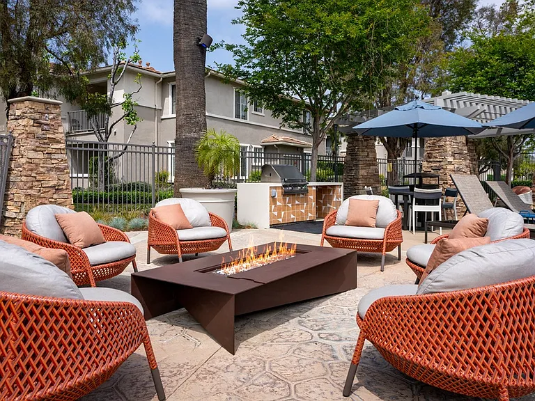 Outdoor Fire Pit Lounge with Woven Chairs and Poolside Seating Nearby