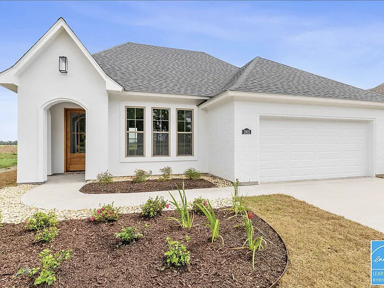 Front of the home featuring an attached two-car garage, attractive landscaping, and beautifully maintained flower beds that create a warm and inviting curb appeal