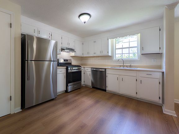 Kitchen with brand new stainless steel refrigerator and brand new gas range with range hood