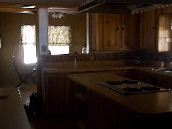 LARGE ISLAND KITCHEN WITH LOTS OF CABINETS, BREAKFAST AREA WITH BAR STOOLS, AND PINE WOOD WALLS.