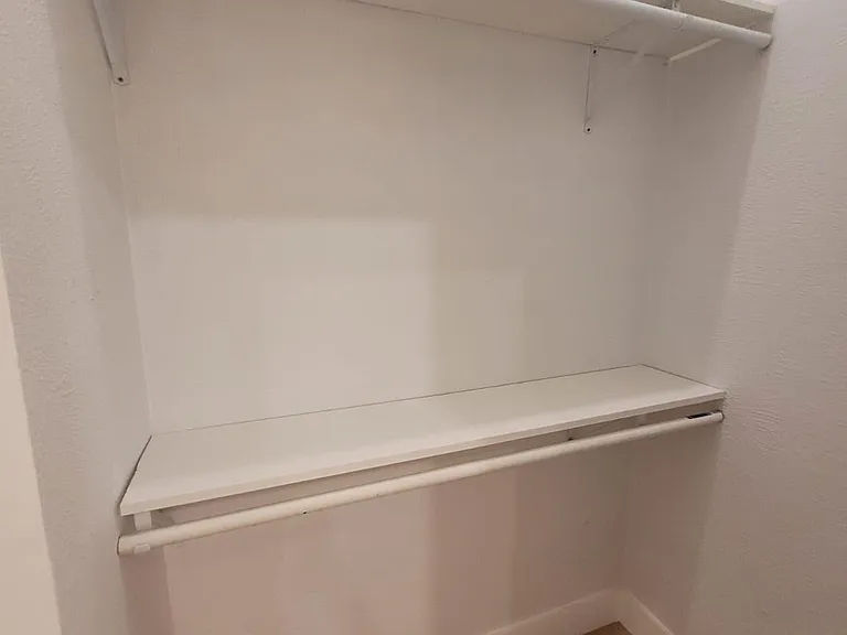 Reach-in closet with a built-in shelf and hanging rod, offering practical storage for clothing and essentials.