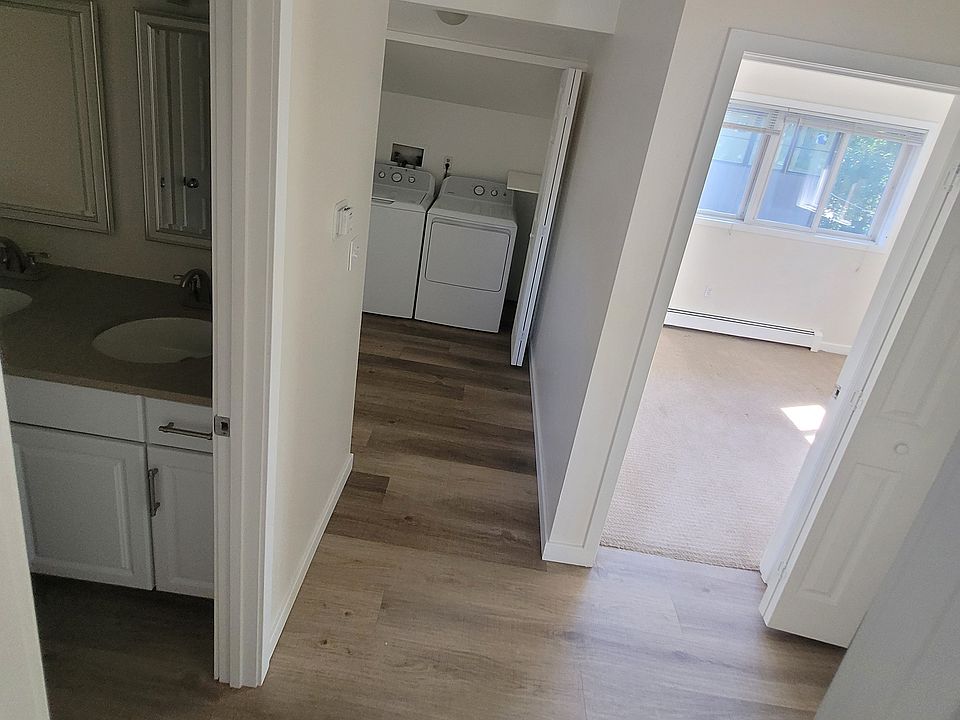 hall view looking into bedroom and showing laundry area and bathroom's dual vanity area