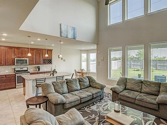 Family room is open to the kitchen and breakfast area. Wall of windows view the large back yard and covered patio.