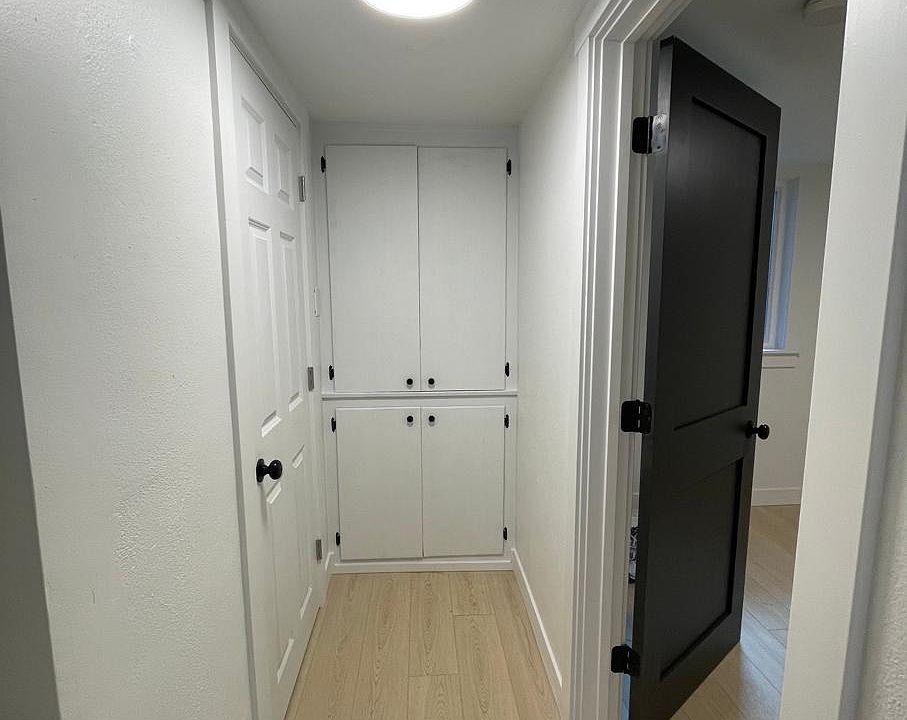 View from kitchen into hallway. Storage at the end of the hall. Bathroom door on left. Second bedroom on right.