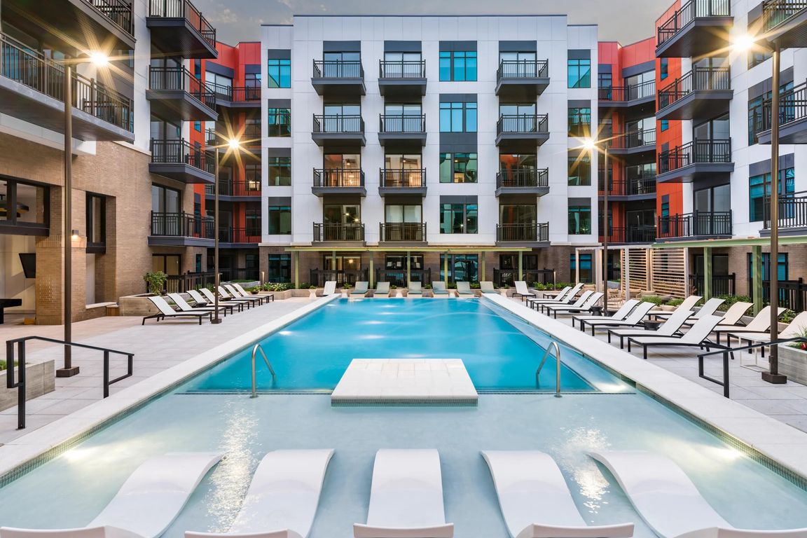 Resort-style pool courtyard with in-water loungers, sundeck seating, and private balconies surrounding the space.