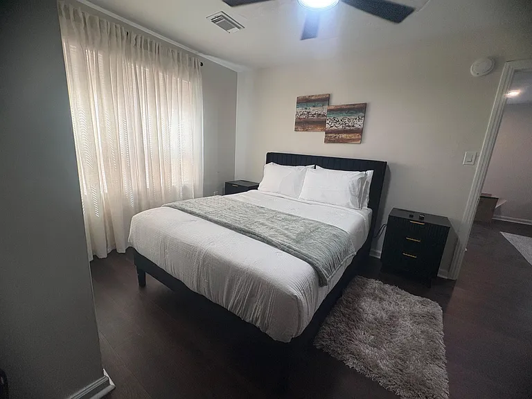 Well-appointed bedroom with a queen bed, nightstands, and a large window with drapes for privacy and natural light.