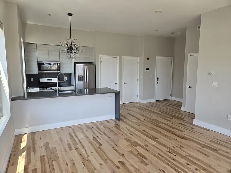 Main living space with view of entry and in-unit laundry and storage (current photo).