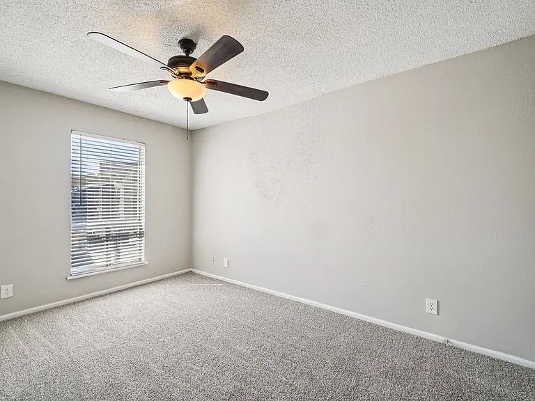 Step into comfort at The Riley Apartments. This spacious bedroom features natural light and a modern ceiling fan, perfect for relaxation. Enjoy a welcoming atmosphere in a community you'll love. Schedule your tour today to see your new home!