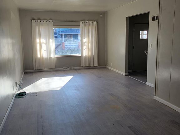 Living room from dining area; bright open windows. New paint and new floors.