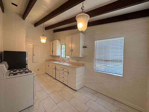EAT-IN KITCHEN WITH BEAMED CEILING, UPDATED FLOORING AND LIGHTING, THREE WINDOWS, VINTAGE TILE