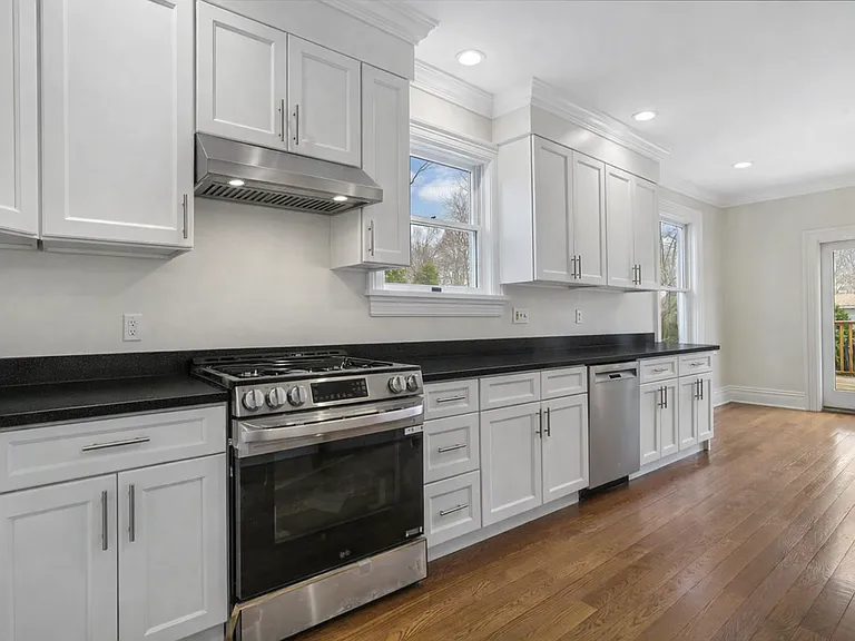 Newly Renovated Eat_in Kitchen Showcasing Quartz Countertops, Stainless Steel Appliances, and Glass Sliders to Deck and Backyard.