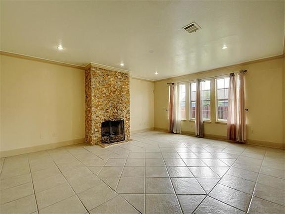 Light-filled family room with tiled floors and brick fireplace.