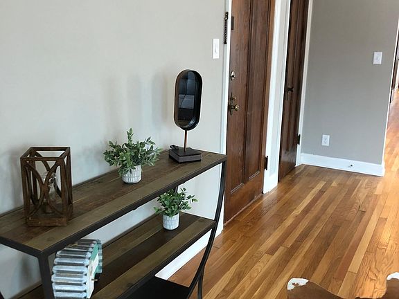 More of the living room. The first brown door is the front entrance into the apartment. The next brown door is a closet.