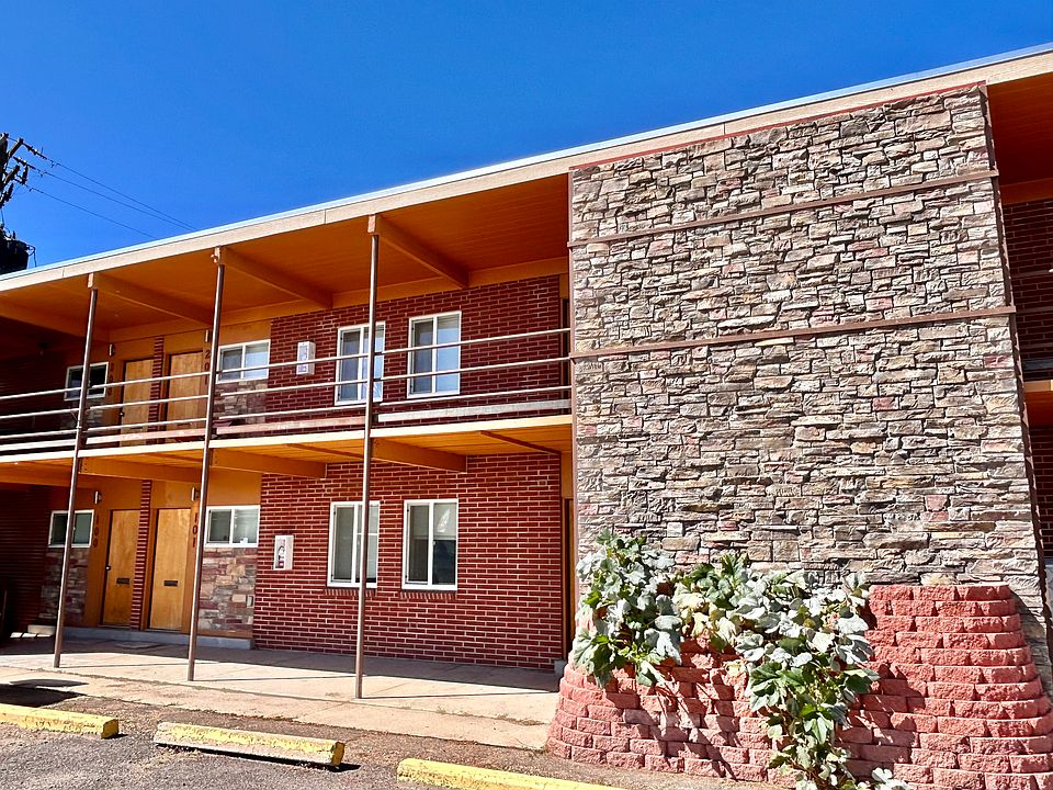 Charming two-story brick apartment building with a modern stone accent wall and inviting double-door entry, basking in bright sunlight.