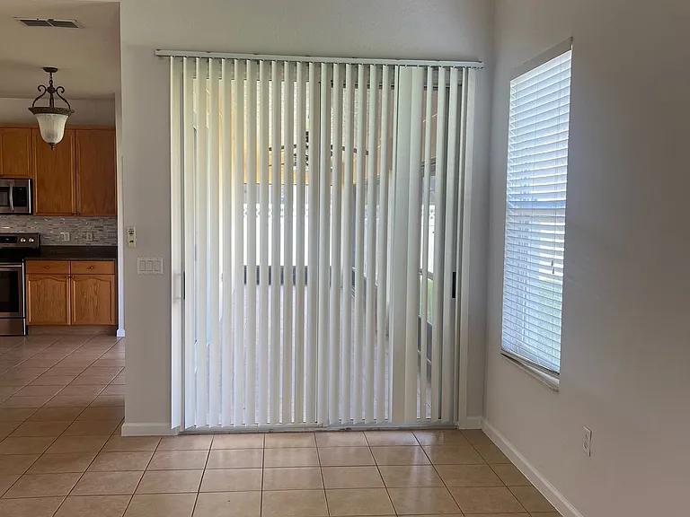 77 - Living room area with tile floor and access to backyard through sliding doors.