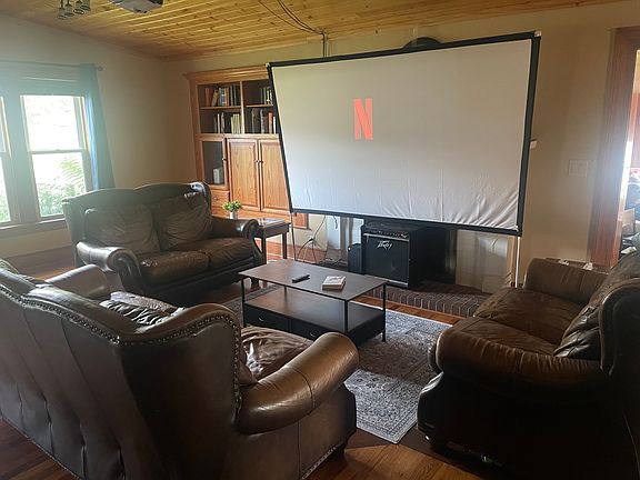 Open-concept living room with leather seating and a projector screen_perfect for movie nights, gaming nights, the sky's the limit. Fire TV Stick included.
