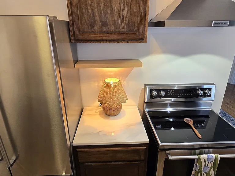 Stainless electric cook-top range stove with vented hood.