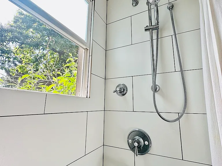 Luxurious dual shower system featuring a rainfall showerhead and a separate wall-mounted showerhead with multiple spray settings