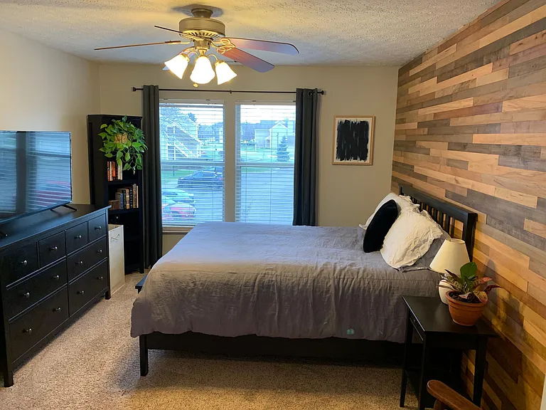 Spacious master bedroom with a gorgeous wood accent wall and ensuite bathroom.
