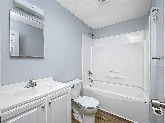 Bright, modern bathroom with elegant white fixtures, sleek vanity, and a soothing blue-gray wall tone.