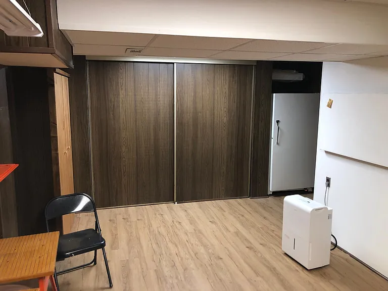Multipurpose room view to sliding doors hiding storage closet and shelves. Next is the Freezer and short hall leading to laundry room.