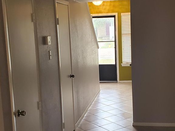 View from living room area to front entry . Air conditioner room on left and then large closet storage on left has built in desk area was used as a computer nook by previous tenant.