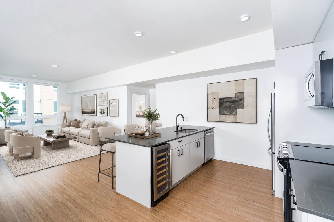 Open-concept kitchen with a center island, built-in wine cooler, and seamless flow into a bright living area filled with natural light