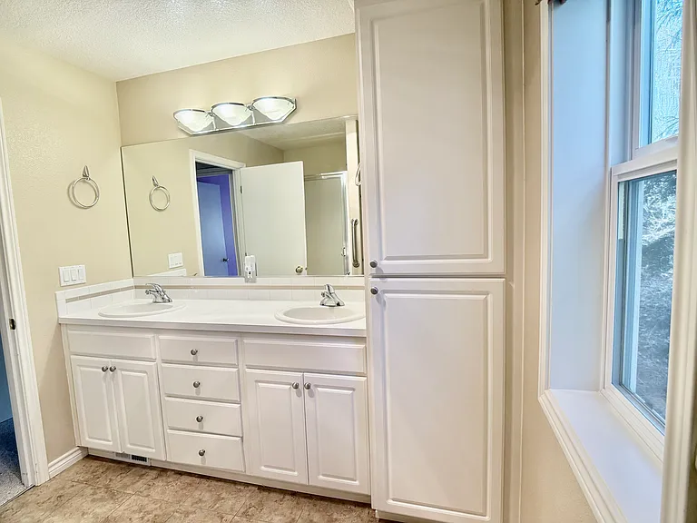 Generous double-sink vanity complemented by an expansive storage shelf, offering both functionality and ample space.