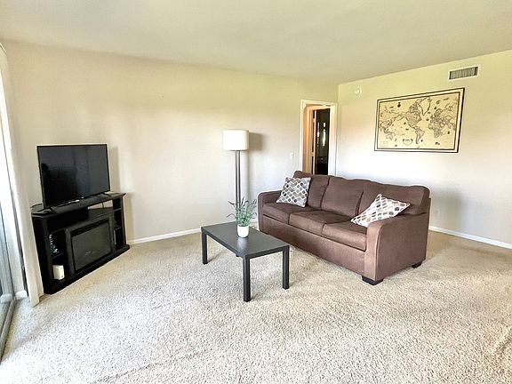 Living room with a view of the Strip and golf course. Incudes sleeper sofa, tv with a stand, WiFi router, coffee table, lamp, picture on the wall, decorative pillows