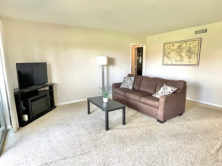 Living room with a view of the Strip and golf course. Incudes sleeper sofa, tv with a stand, WiFi router, coffee table, lamp, picture on the wall, decorative pillows