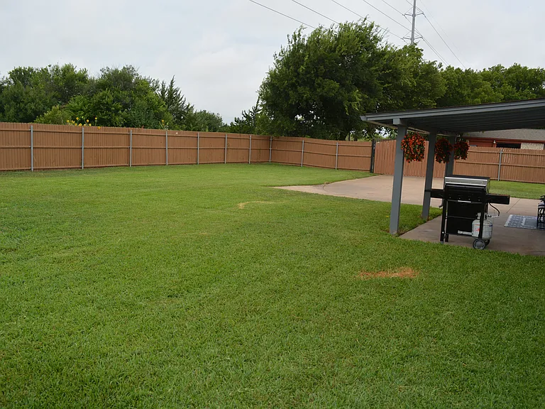 Full-fenced and spacious backyard with a covered patio, outdoor furniture and a grill for outdoor family fun!