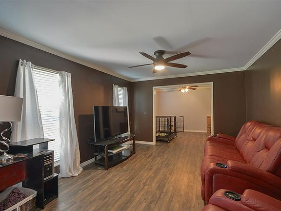 This light and bright living area is the perfect layout for entertaining or just relaxing! Featuring dark stained ceiling fan, wood flooring, large windows with blinds, and crown molding!