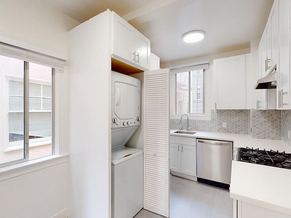 Kitchen with cabinets, stove, range hood, sink, and an in-unit washer and dryer