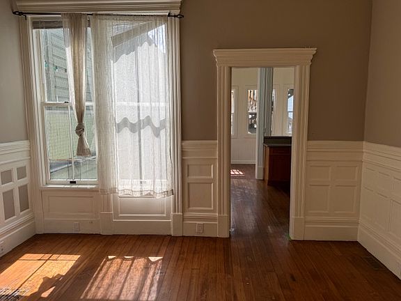 same family room off kitchen from other angel and w no furniture- view through door is to kitchen and then to sun room - this room has a tiled fireplace to the left - hutch on wall behind where photo taker would be standing - lovely room :)