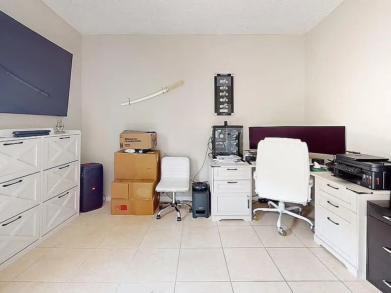 Chic home office featuring modern white storage cabinets, sleek monitors, and cozy seating ideal for productivity.